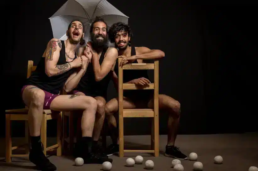 Three funny guys performing on stage sitting in chairs