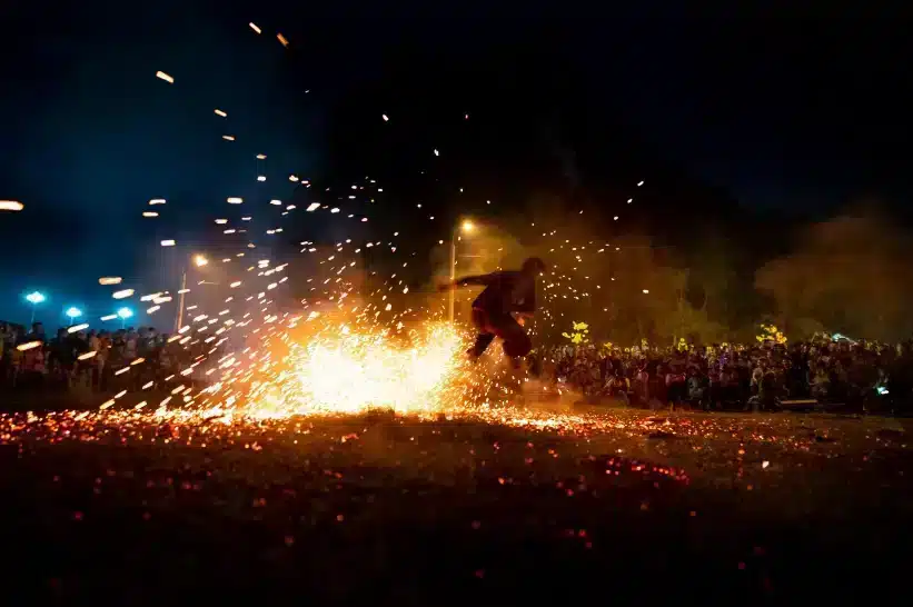 A person sparking a fire in the center of a crowd
