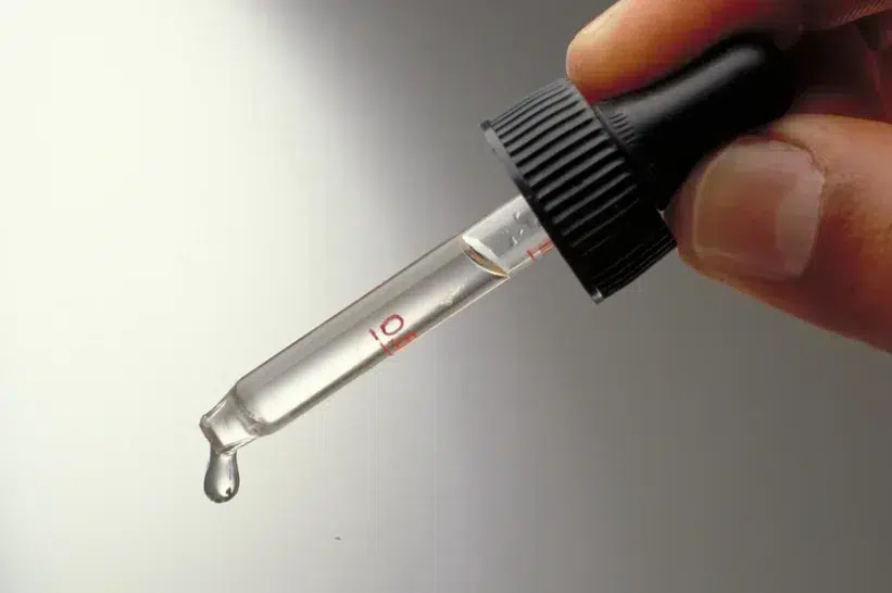 A hand squeezing a dropper filled with distilled Delta 10