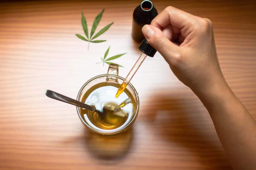 a hand holding a dropper into a cup of tea