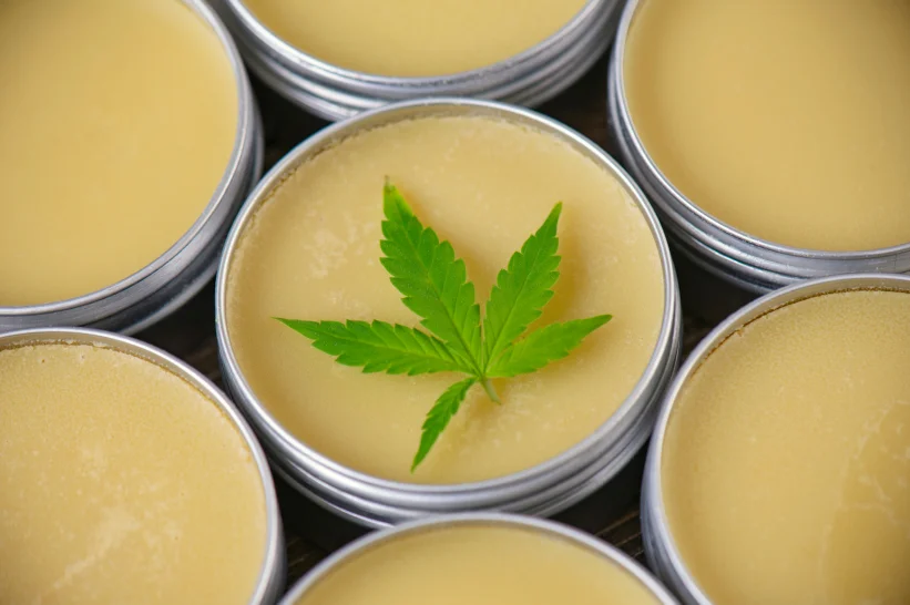 a group of round containers containing THC water soluble infused salve with a green leaf on top