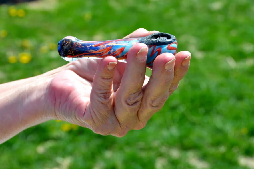 Hand holding a colorful smoking glass hash pipe