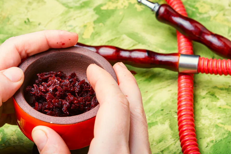 Hands holding bowl of tobacco and hash