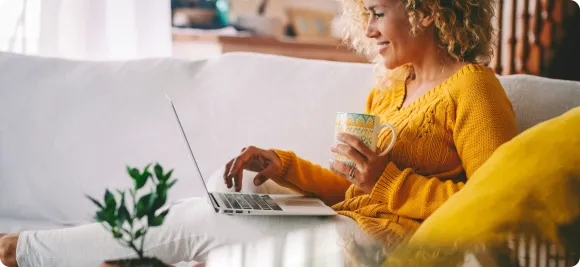 Woman relaxing on a couch with a laptop and a mug