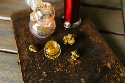 a glass pipe with a THCA concentrate in it next to a small container