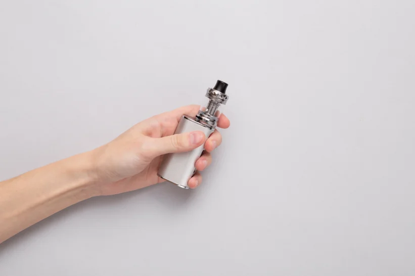 a hand holding a vape with an empty tank